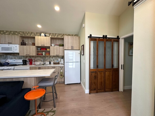 Kitchen area & closet with wooden doors w/full-sized stacked washer/dryer behind - 1490 Ash St Unit Furnished Napa ADU  B