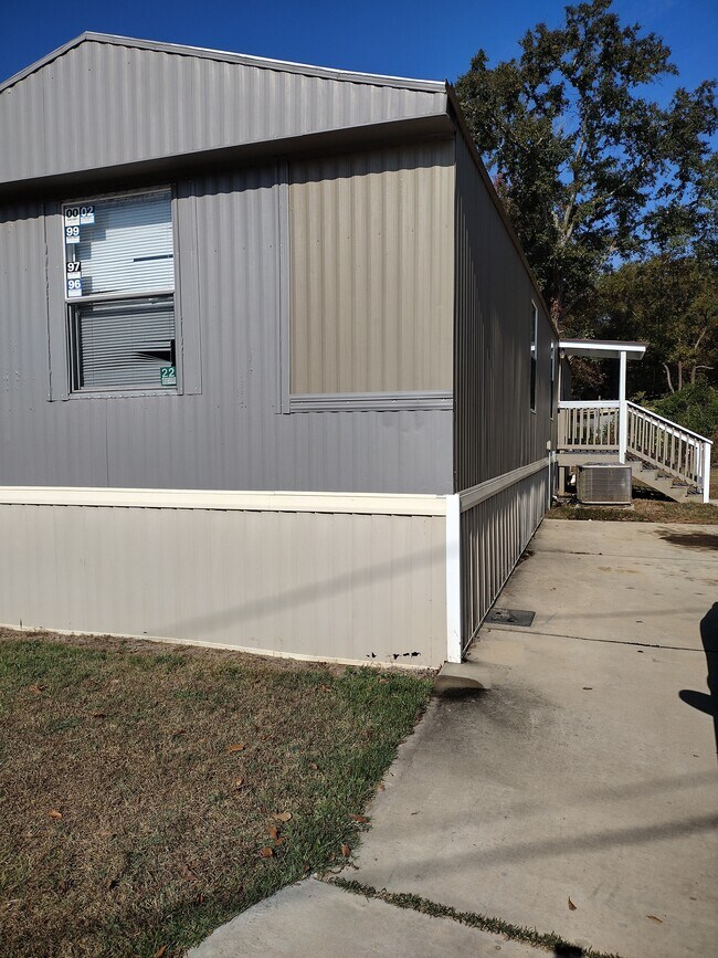 Puerta trasera y zona de aparcamiento con porche cubierto. - 716 N Houston Lake Blvd