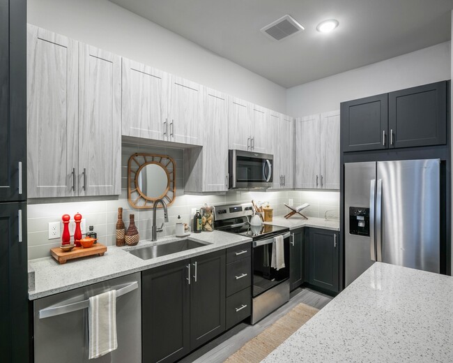 Elevate your culinary skills in our modern kitchen, featuring quartz countertops, shaker white cabinets with satin pool, and stainless steel appliances. - Modera EaDo Apartments