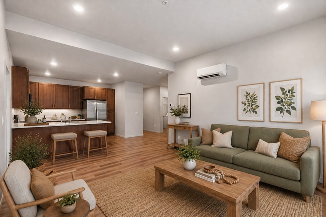 Inviting open-concept living area featuring a modern kitchen with wooden cabinetry, plank flooring, and stainless steel appliances. - Lofts at Garden District