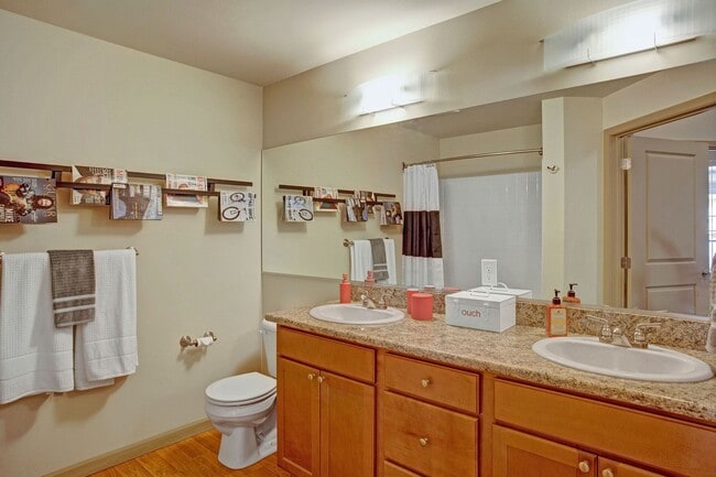 A spacious bathroom with double sinks, a large mirror, and lots of cabinet storage - Riverside 9