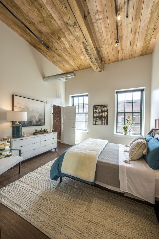 Dormitorio espacioso en apartamento con techos altos y detalles de vigas de madera a la vista.