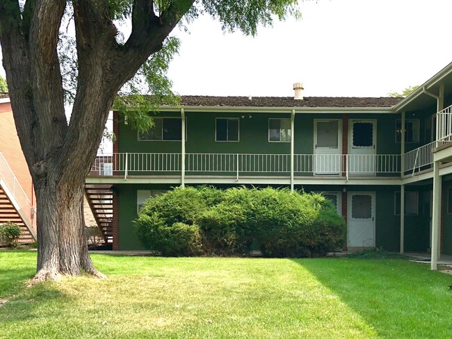 Cozy two-story apartment exterior with lush greenery and a welcoming courtyard.