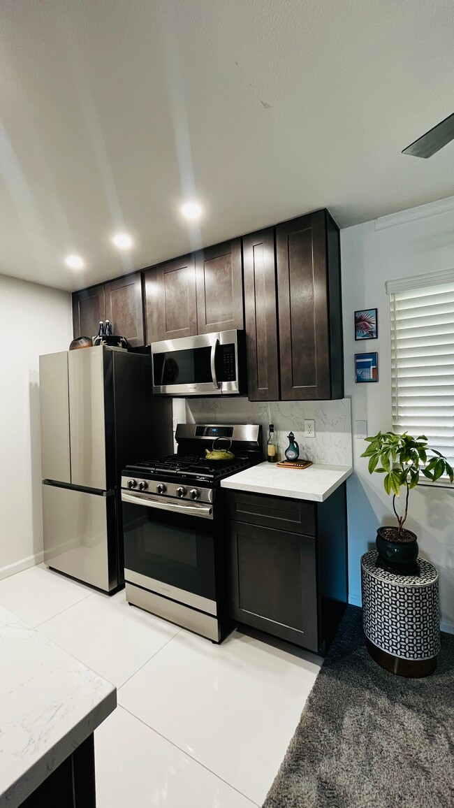 New kitchen With stainless steel refrigerator, dishwasher, microwave, and stove. Garbage disposal - 6600 Warner Ave Unit Modern Condo