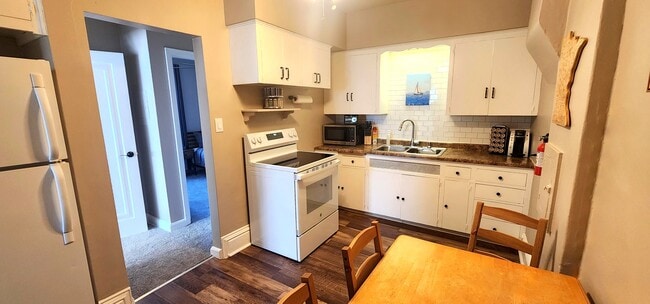 Fully equipped kitchen with oven, microwave, coffee station, and Minnesota-themed art. - 822 E 4th St Unit #1