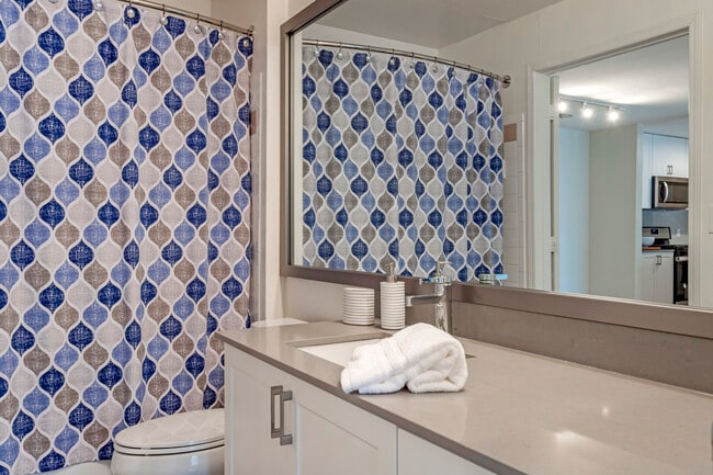 Renovated Package I bath with white cabinetry, quartz countertops, and hard surface flooring