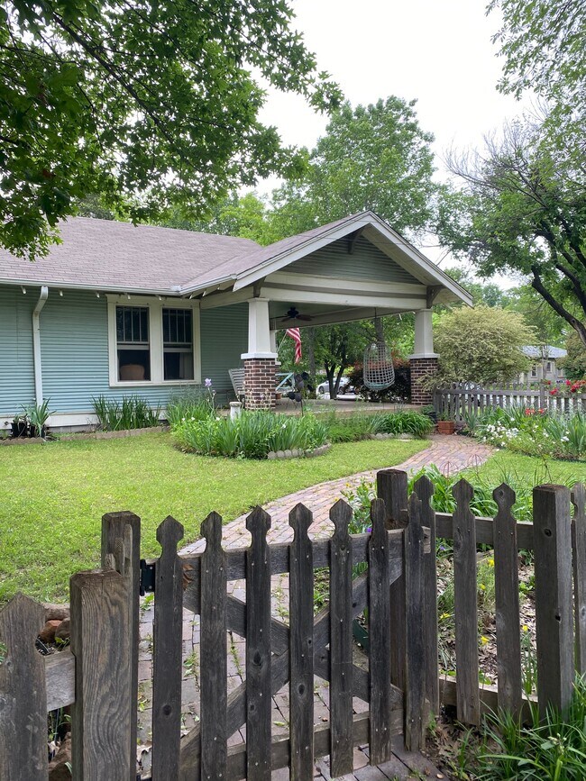 Side view of porch and garden with charming cottage fence. - 1003 Egan St
