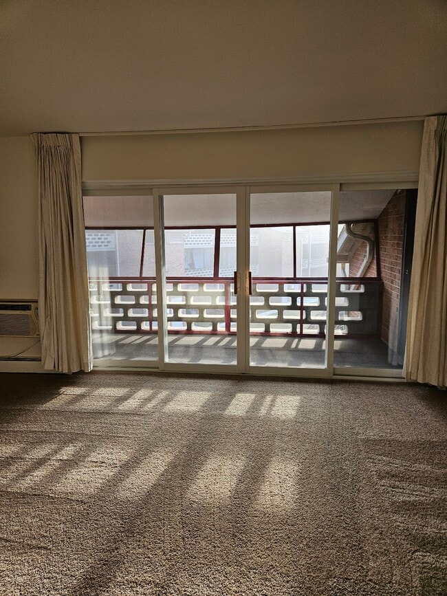 Embrace the warmth of natural light in this inviting living area with easy access to a cozy balcony. - Lake Club Apartments