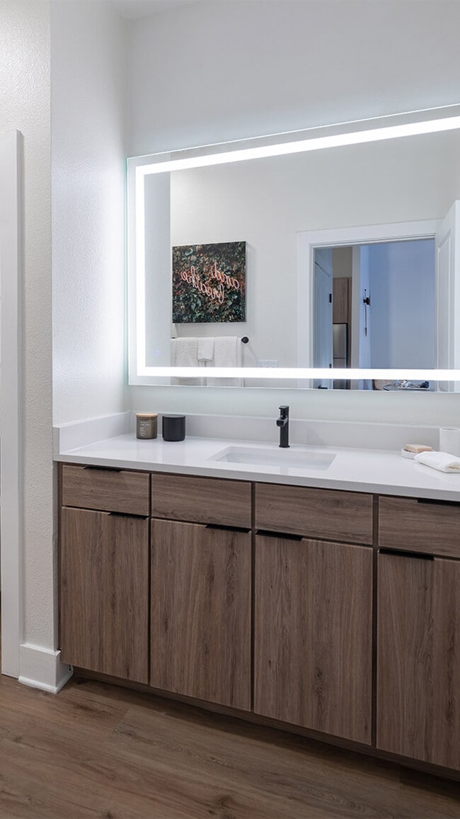 Baño del apartamento con piso estilo madera y espejo de tocador LED.