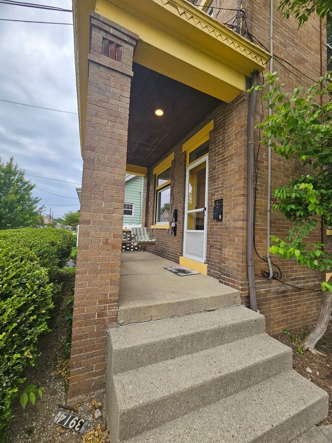 Front porch that is part of unit 1 with a porch swing. - 3914 S Madison Ave Unit Floor 1