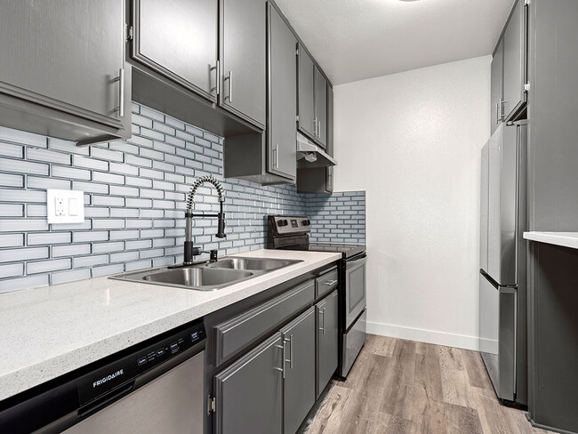 White tiled kitchen with stainless steel fridge, microwave, and oven. - Chandler Circle Apartments