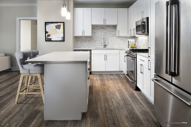 Signature Collection kitchen with white cabinetry, light grey quartz countertops, white marbled subway tile backsplash, stainless steel appliances, and hard surface flooring