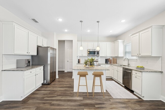 View of the kitchen and entry hallway. Offering bar seating, plenty of cabinet space and granite countertops.