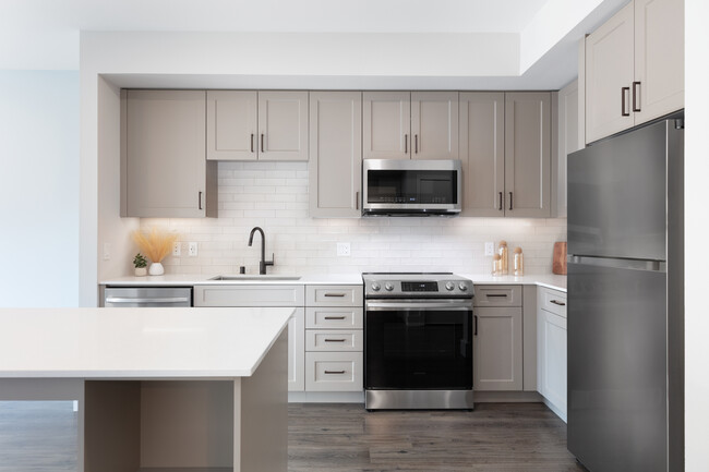 Coming Soon - New West Phase apartments - Finish Package III Kitchen with stainless steel appliances, white quartz countertops, grey cabinetry, pendant lighting, and hard surface flooring (Representative photo) - Avalon Hunt Valley Apartments