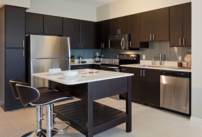 Modern kitchens with stainless steel appliances, tile backsplashes and moveable islands - Modera Douglas Station Apartments