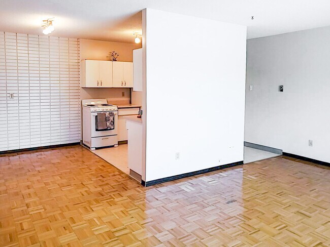 The open-concept layout at 1025 Munroe Apartments seamlessly connects the living room, dining area, and kitchen for a modern living experience. - 1025 Munroe Avenue