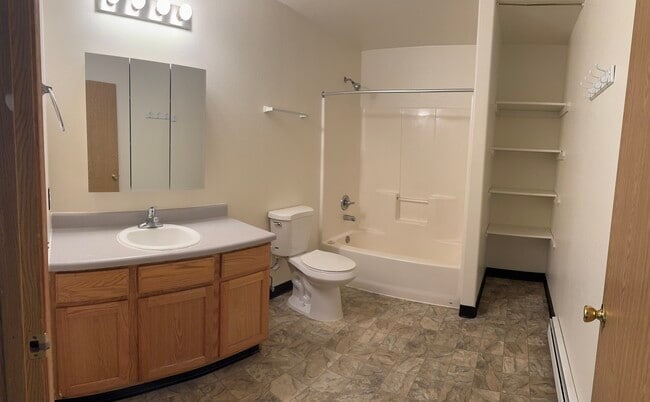 Well-lit bathroom with a full tub/shower combo, extended vanity, and built-in shelving - 2979 Badger Rd Unit D