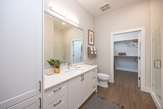 Primary bath with white quartz countertop, white cabinetry, and hard surface vinyl plank flooring