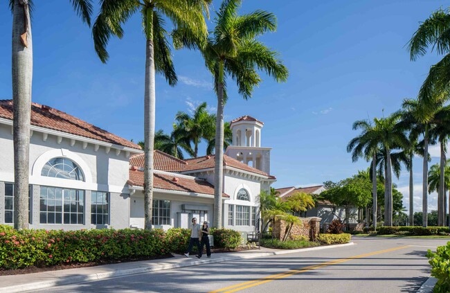 A broad walkway leads past the clubhouse toward the community amenities.