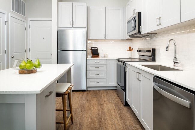 New West Phase - Finish Package III Kitchen with stainless steel appliances, white quartz countertops, grey cabinetry, and hard surface flooring