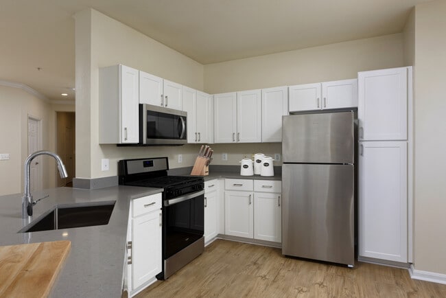 Renovated Package I kitchen with stainless steel appliances, grey quartz countertops, white cabinetry, and hard surface flooring