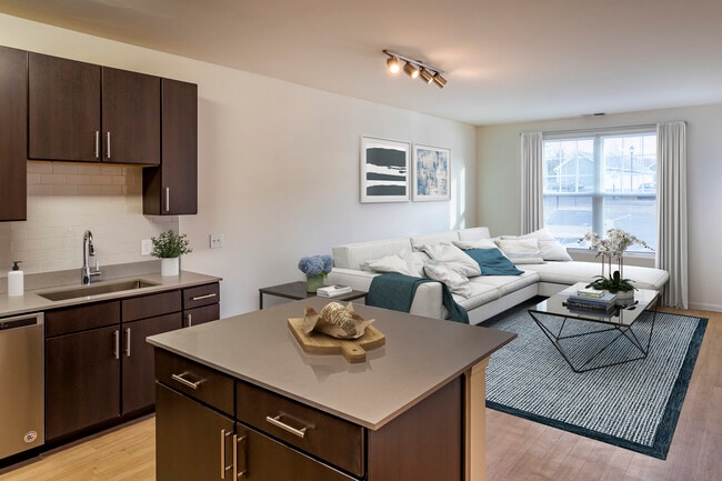 Newly renovated apartment homes feature kitchens with espresso cabinetry, grey quartz countertops, stainless steel appliances, grey tile backsplash, and hard surface flooring