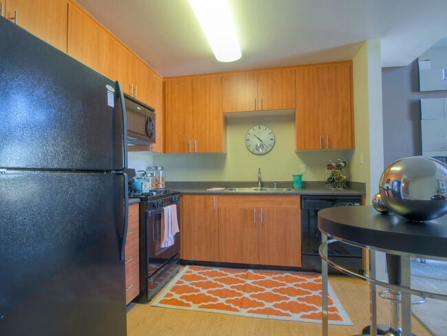 Classic Package kitchen with black appliances, grey speckled laminate countertops, oak cabinetry, and hard surface flooring