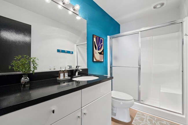 Renovated Package I bath with black laminate countertop, white cabinetry, and updated hard surface flooring