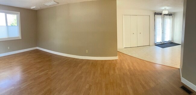 Living room and dining area. Laundry/utility area behind bifold doors. French doors to back patio. - 1152 NE Viking Ct