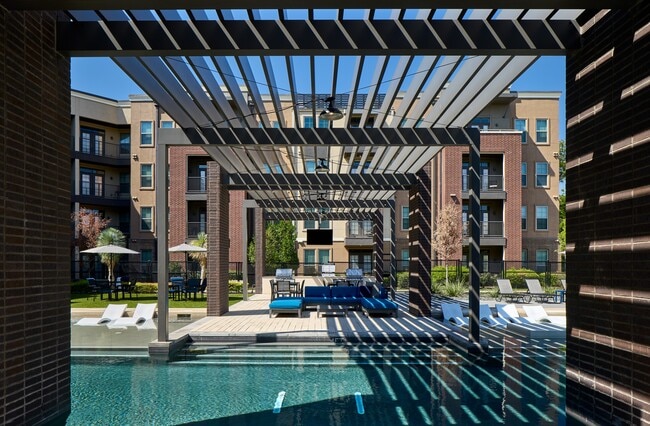 Piscina estilo resort con zona para tomar el sol y terraza.