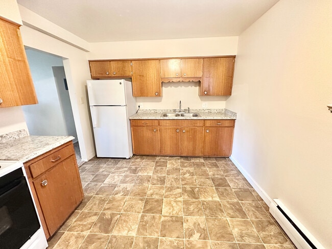 Cozy kitchen with warm wooden cabinetry, sleek countertops, and modern appliances, perfect for culinary creativity. - 7250-7290 Newton Street