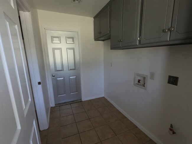 View of utility room with door to garage; there is a space for an additional fridge or upright freezer - lots of cabinet space - 415 W Guthrie St Casa