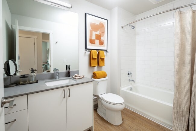 Bath with grey quartz countertops, white cabinetry, and hard surface flooring