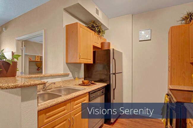 A kitchen with light cabinets and black appliances - Visions Apartments