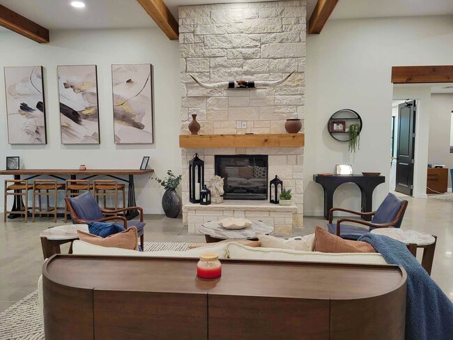 Stone fireplace with longhorn décor, wood mantle, and cozy lounge seating in a modern clubhouse common area