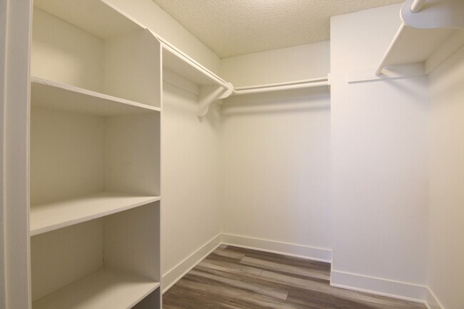 Vestidor con un amplio espacio de almacenaje, estanterías, y barras para colgar.
