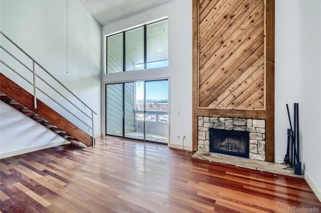 Living room with vaulted ceilings, high windows, balcony door, mountain views, and fireplace - 14282 E Tufts Pl Unit Q11
