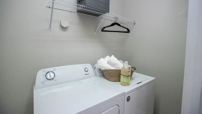 Enjoy the ease of in-home laundry with a full-size washer and dryer set, complete with additional overhead shelving for organized storage.