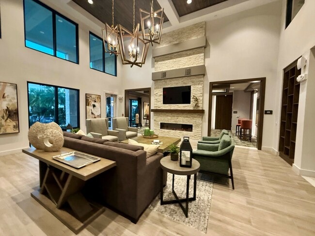 Experience elegance in this modern living room, boasting upscale furnishings and ample natural light at Integra Palms. - Integra Palms Apartments
