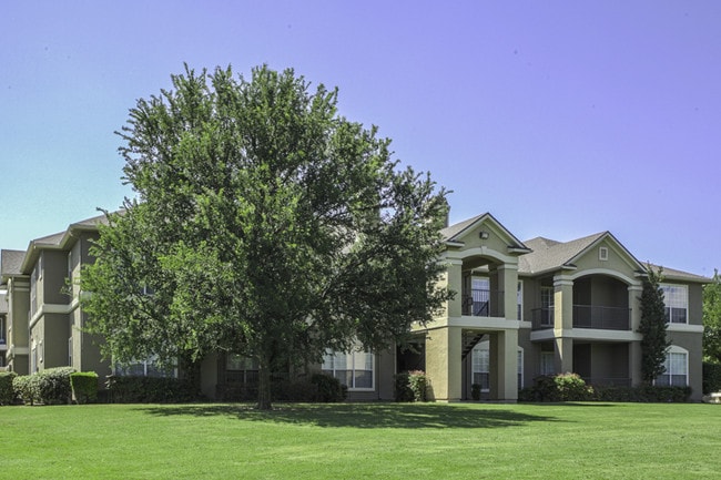 Terrenos ajardinados con árboles maduros y cambio de color estacional - Legends at Chase Oaks