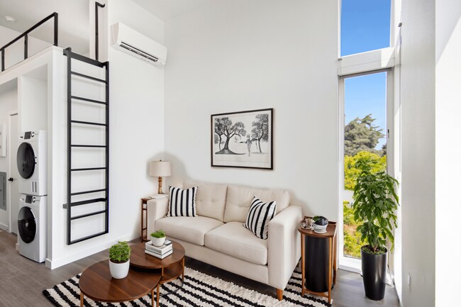 Relax in the cozy studio loft living room featuring a white couch and rug at Alt Capitol Hill.