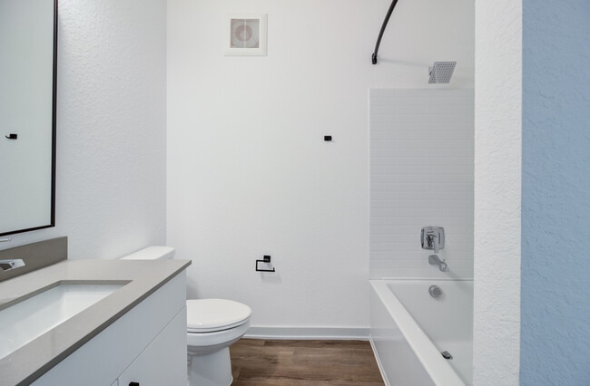 A clean, well-appointed bathroom featuring a large vanity and sink, shower and tub combo, and a spray pattern showerhead — functional and finished.