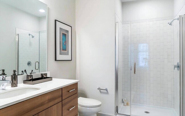Elegant Bathroom Featuring Glass Shower and Woodgrain Cabinetry - The Madison at Marshfield