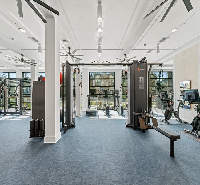 Bright and spacious fitness center equipped with modern exercise machines, large windows, and sleek design. - Elan Crown Point