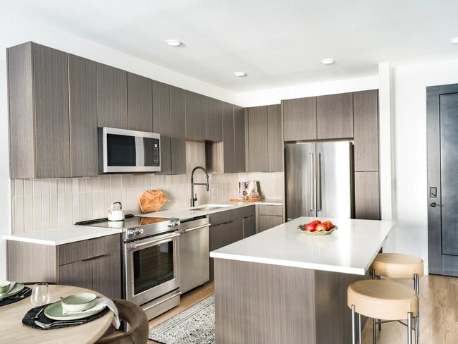 Contemporary kitchen design with rich-toned cabinetry, stainless steel appliances, and a spacious island perfect for cooking or casual dining.
