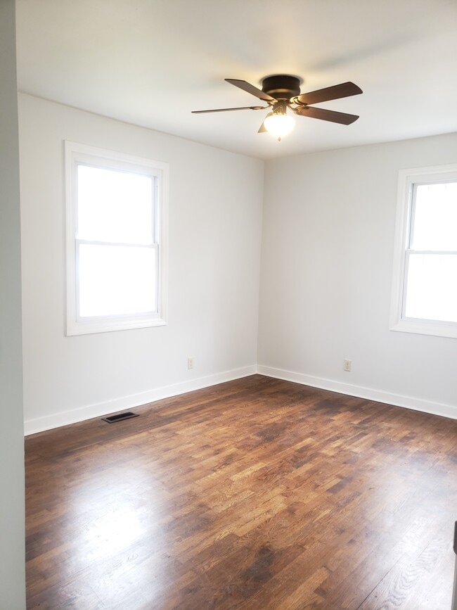 Habitación de buen tamaño con ventiladores de techo, suelos de madera y ventanas que permiten la entrada de luz natural. - 2713 Jenkins St
