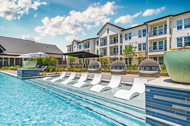 Piscina estilo resort con amplia terraza y césped para juegos - Atlas Bluewood Apartments