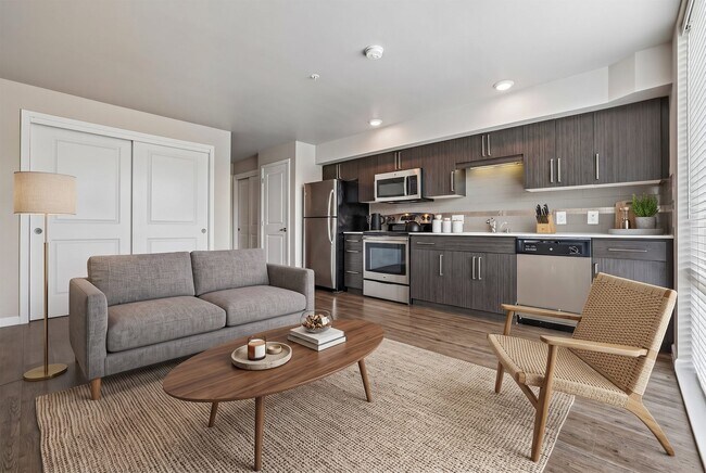 Open-concept layout featuring a modern kitchen with stainless steel appliances and an adjoining living area at Ludwig Apartments.