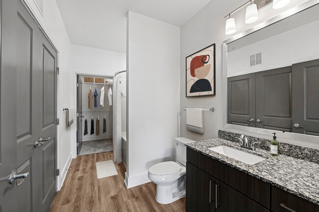 Bath with espresso cabinetry, speckled granite countertops, and hard surface flooring