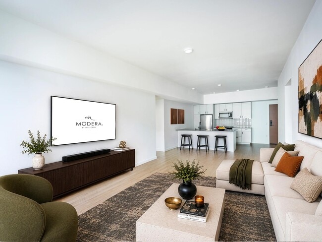 Open living area with clean-lined finishes, a generous lounge space, and a kitchen with bar seating designed for gathering and everyday comfort.